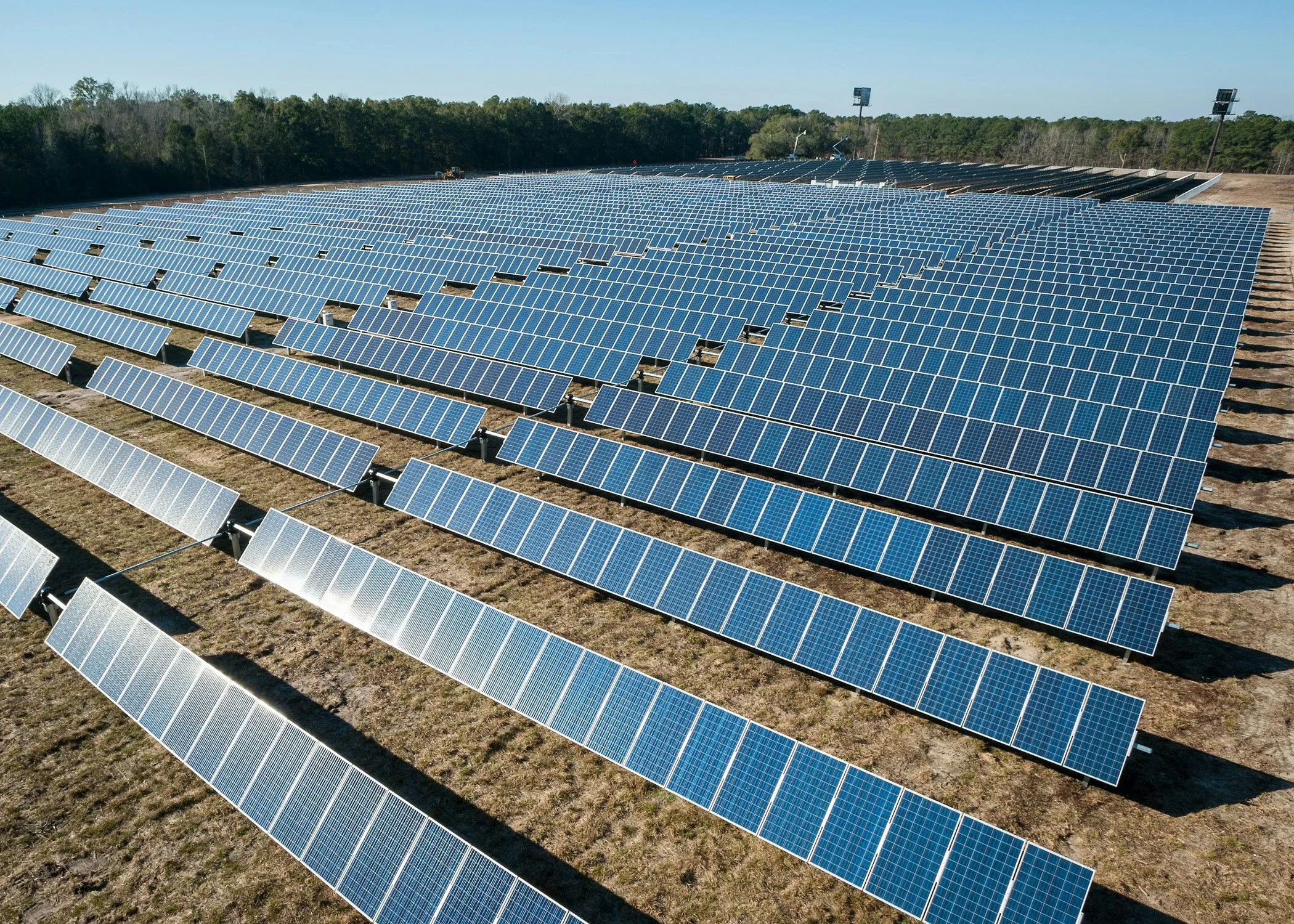 Large ground-mounted solar array under construction on cleared terrain